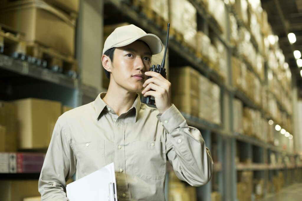 Young logistics staff using walkie-talkie in warehouse